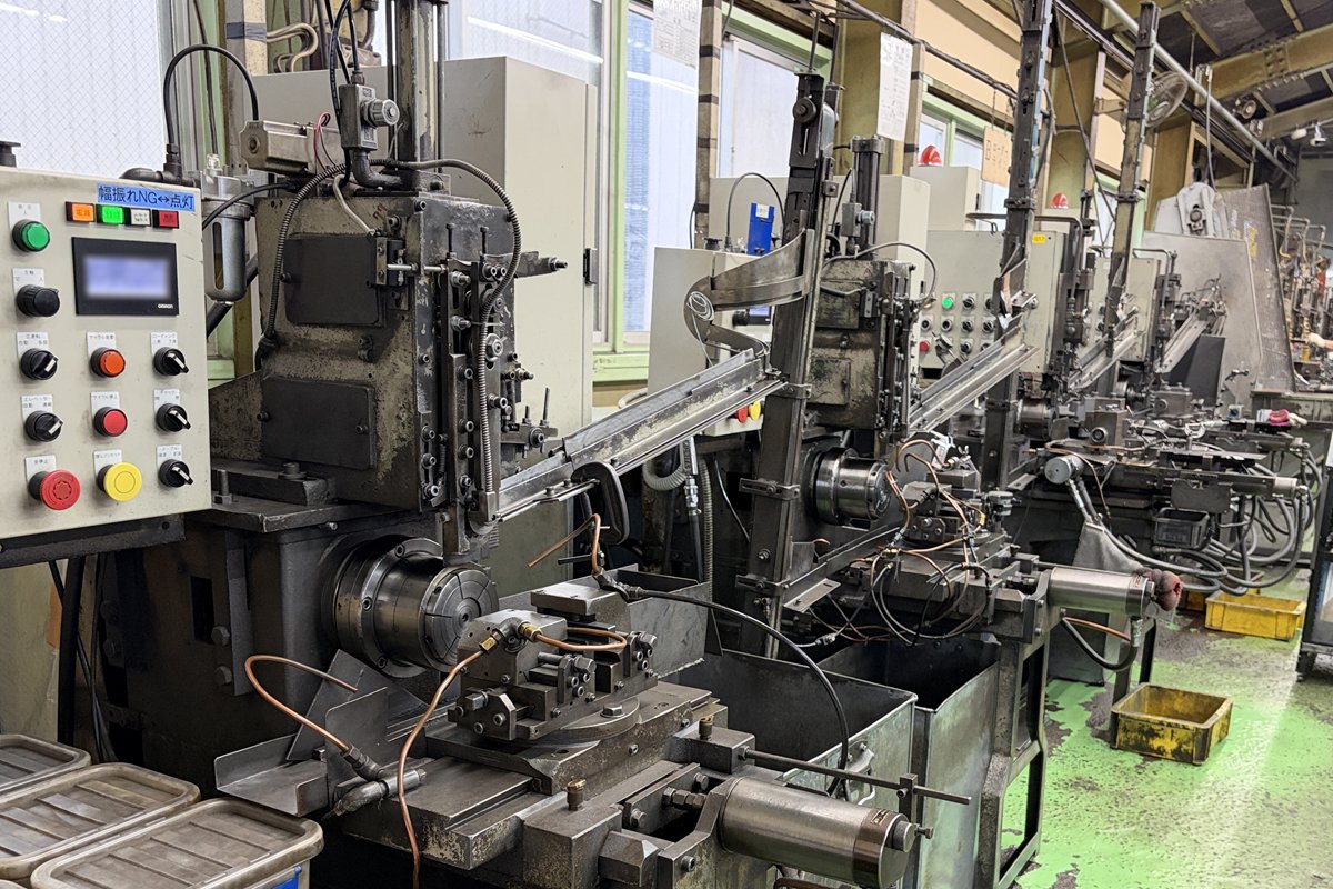 単能盤のローダーライン。手前の機械の操作盤と主軸、その奥に同じ単能盤が並ぶ